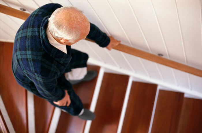 Elderly man unsteady on staircase.