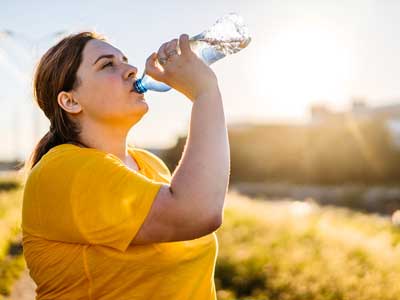 Una mujer bebiendo una botella de agua después de hacer ejercicio.