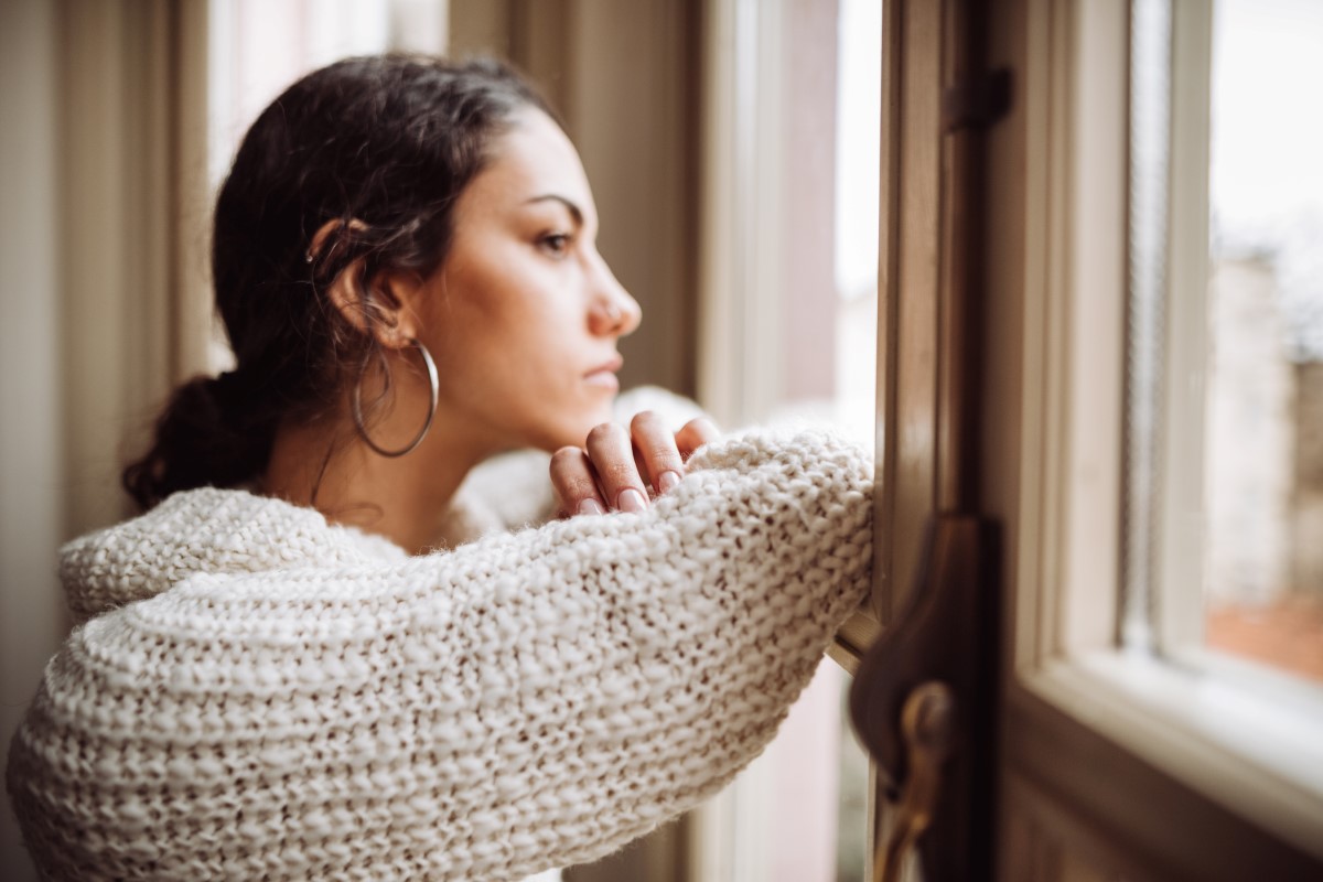 mujer que lucha con la salud mental mira por la ventana