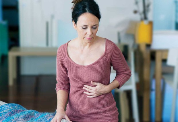 Mujer sosteniendo su estómago con expresión de dolor