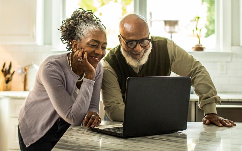 A couple in their kitchen taking a health risk assessment on a laptop