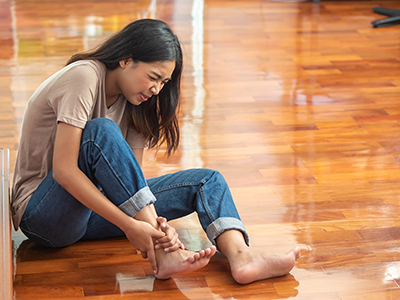 girl sits on floor holding injured ankle