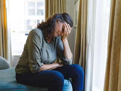 woman in distress sits by window